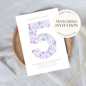 May include: A white invitation card featuring the number 5 composed of colourful mermaid illustrations. Text includes party details and "Matching Invitation". The card rests on a wooden plate. Measurements are not applicable.