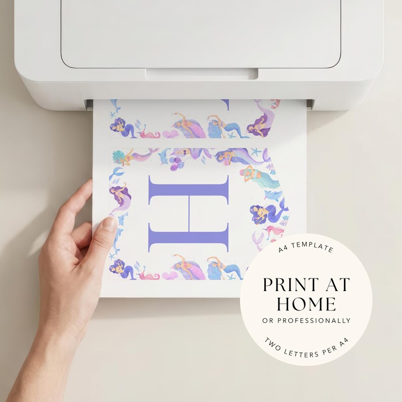 May include: A4 template being printed from a printer. The printed sheet features a large purple letter 'H' surrounded by a border of watercolour mermaids in shades of purple, blue, and pink. Text on the sheet reads 'PRINT AT HOME'.