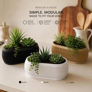 May include: Three oval modular planters in black, white, and wood-toned finishes, each featuring a vertical wavy texture. The planters contain various green succulents and trailing plants. Text on the image reads: MODULAR PLANTER. SIMPLE. MODULAR. MADE TO FIT YOUR SPACE.