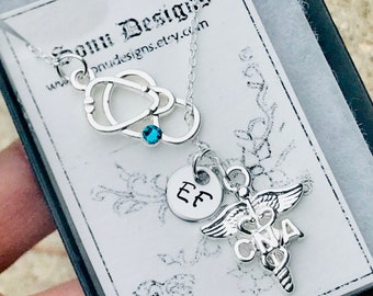 May include: Silver necklace with a stethoscope charm, a small round charm with the initials "EE" and a caduceus charm with the letters "CNA". The necklace is on a white background with the text "Somi Designs" and a website address.