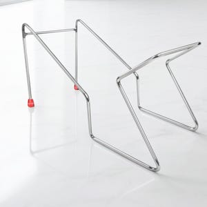 May include: A contemporary, silver-coloured pot and pan organiser. The organiser is made of metal and has a geometric design. The base has red feet. The organiser is designed to hold multiple pots and pans.