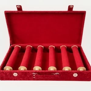 May include: A rectangular jewelry display case covered in red velvet fabric. The open box features a hinged lid and six horizontal red velvet-covered cylindrical bars designed for holding bracelets or watches, secured by a metal latch on the front.