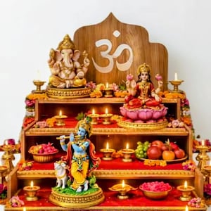Op de afbeelding: Een houten altaar met meerdere niveaus met hindoe-goden, waaronder Ganesha en Lakshmi, versierd met kaarsen, bloemen en offers. De achtergrond toont het Om-symbool. Het altaar is versierd met rode stof.