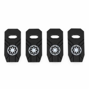 May include: Four black rectangular plastic components with a hexagonal cutout at the top and a white circular emblem featuring a stylized starburst design in the center. Each piece has molded geometric lines radiating from the central emblem.