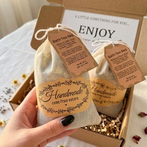 May include: A gift box with two handmade bath tea bags. Each bag has a tag with product information and a label that reads "Handmade come from nature." The box also includes a card that says "A little something for you... ENJOY."