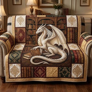 Puede incluir: Una funda de sofá con un dragón blanco leyendo un libro frente a una estantería. La funda tiene un diseño de patchwork con patrones dorados, burdeos y verdes. El tema es la fantasía y la literatura, con libros.