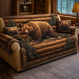 May include: A brown sofa with a bear-themed cover and matching throw pillows. The cover features a large grizzly bear image with a forest scene. The sofa has a light tan frame and sits on a gray rug.