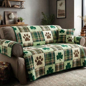 Può includere: Una fodera per divano a quadri verdi e marroni con impronte di zampe e trifogli. La fodera ha un design patchwork con un cuscino abbinato. La fodera del divano è progettata per proteggere il divano.