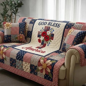 May include: A patchwork sofa cover and cushions in red, white, and blue. The cover features a cross design with floral accents and the words "GOD BLESS America". The design incorporates floral and star patterns, with measurements in centimetres.