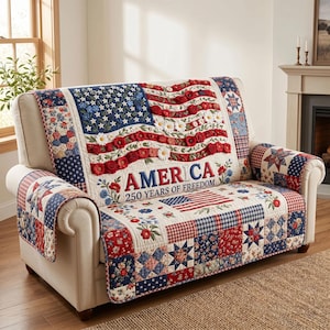 May include: A sofa cover with a patriotic design, featuring the American flag and the text "AMERICA 250 YEARS OF FREEDOM." The cover is made of patchwork fabric in red, white, and blue, with floral and star patterns. It is draped over a cream-coloured sofa.