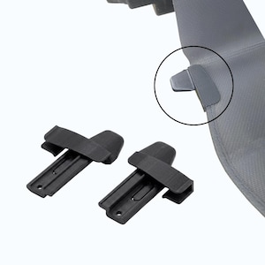 Op de afbeelding: Twee zwarte plastic clips met een rechthoekige basis en een gebogen bovenkant, ontworpen om stof te bevestigen. De clips worden getoond tegen een witte achtergrond, met een close-up van een clip bevestigd aan grijze stof.