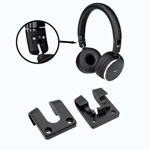 Può includere: Cuffie over-ear nere con dettagli argentati e il marchio "AKG". Sono mostrate due clip di plastica nera sotto le cuffie. Un primo piano mostra il lato destro delle cuffie.
