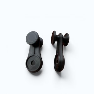 Può includere: Due pomelli per mobili grigio scuro stampati in 3D. Ogni pomello ha una parte superiore e inferiore circolare, collegate da uno stelo con un foro centrale. I pomelli sono progettati con un'estetica moderna e minimalista, adatta per mobili o decorazioni.