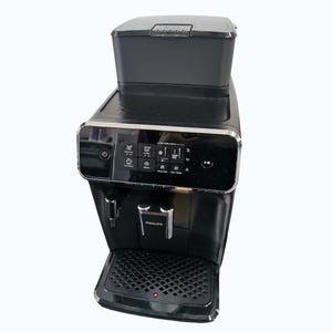 Op de afbeelding: Een zwarte Philips espressomachine met een ingebouwde molen en digitaal display. De machine heeft een waterreservoir, een lekbak en een tuit voor het afgeven van koffie. Het bedieningspaneel heeft verschillende koffie-opties en instellingen.