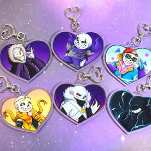 Puede incluir: Llaveros en forma de corazón con personajes de esqueletos de dibujos animados en varias poses y atuendos. Cada llavero tiene un cierre plateado. Los fondos son morados, amarillos y azules. Los llaveros están hechos de acrílico transparente.