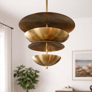 Op de afbeelding: Een moderne, gelaagde kroonluchter met een messing afwerking. De lamp heeft vier cirkelvormige, komvormige kappen die aan een centrale staaf zijn opgehangen. De kappen zijn in verschillende maten, waardoor een gelaagd effect ontstaat.