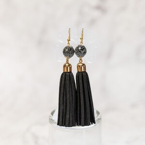 May include: A pair of black tassel earrings with gold accents and a black and white patterned bead.