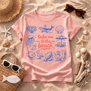 K&ouml;nnte beinhalten: Hellrosa T-Shirt mit Strandmotiv. Das Design zeigt blaue Illustrationen von Meereslebewesen, einen Sonnenschirm und den Text "take me to the beach". Das T-Shirt ist von Strandaccessoires umgeben.