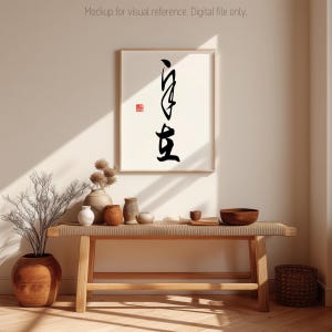 May include: A framed vertical wall art print featuring black Japanese calligraphy characters arranged in a column, accompanied by a small red square seal stamp, displayed in a light-colored wooden frame on a plain wall.