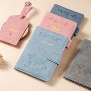 May include: A collection of passport holders and a luggage tag. The holders are blue, pink, and gray, featuring a world map embossed on the front and the text PASSPORT. Two holders are personalized with the names Sarah and James in gold lettering.
