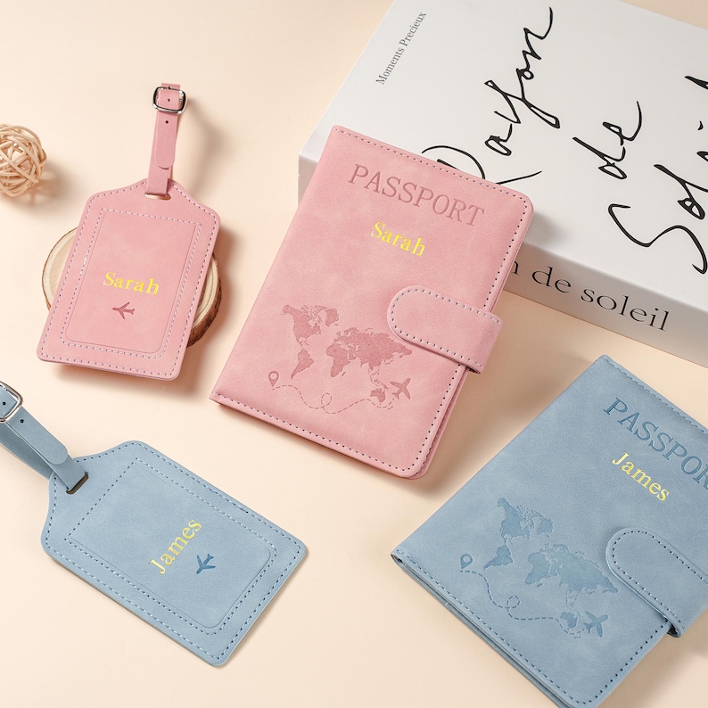 May include: Two passport holders and two luggage tags in pink and blue. The pink set is personalized with the name Sarah and the blue set with James. Each item features a world map graphic, an airplane icon, and the word PASSPORT in gold text.