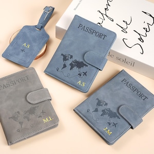 May include: Three rectangular passport holders in blue and gray with a world map print, a snap closure, and the word PASSPORT embossed on the front. Each holder features gold-colored initials and a matching luggage tag with the initials A.S.