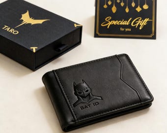 May include: Black leather wallet with a Batman logo and the text "BAT ID". The wallet is next to a black box with a gold bat logo and the word "TARO". A card with "Special Gift for you" is also present.
