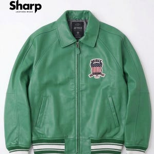 May include: Green leather jacket with a zip-up front, a collar, and a patch on the chest. The jacket has white and green striped cuffs and a white and green striped hem. The brand name "Sharp Leather Wear" is in the top left corner.