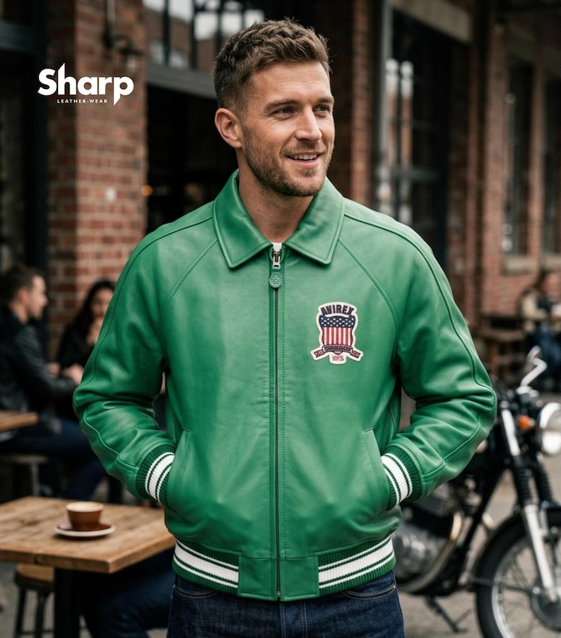 May include: Green leather jacket with a white and green striped trim on the cuffs and hem. The jacket has a zipper closure and a patch on the chest with the text "AVIREX" and an American flag design. The brand "SHARP LEATHER WEAR" is in the top left corner.