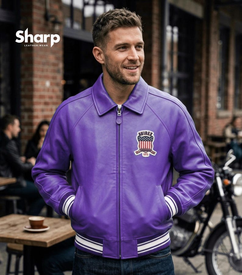 May include: A purple leather jacket with a white and black striped trim on the cuffs and hem. The jacket has a zipper closure and a patch on the chest with an American flag design. The jacket is from Sharp Leather Wear.