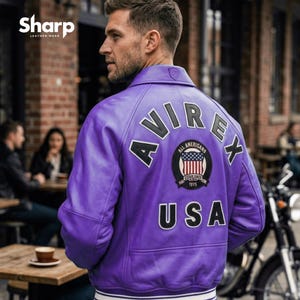 May include: A purple leather jacket with the word "AVIREX" across the back, along with a patch featuring the American flag and the text "ALL AMERICANS" and "USA". The jacket has a white and navy blue striped trim at the waist and cuffs.