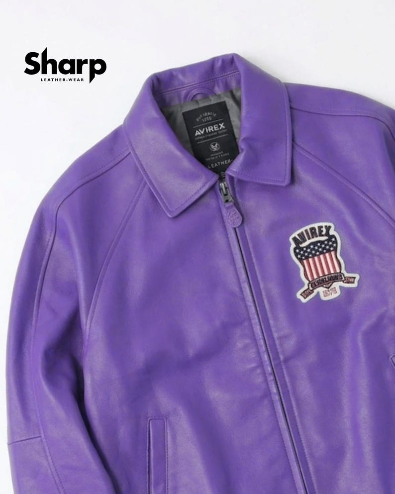 May include: A vibrant purple leather jacket with a collared neckline and a zipper closure. The jacket features a patch with a patriotic design and the brand name "AVIREX". The upper left corner displays the text "Sharp Leather Wear".