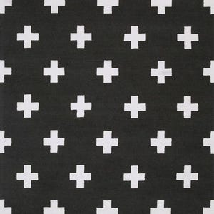 Puede incluir: Una alfombra rectangular con un patrón repetitivo de signos más blancos dispuestos en una cuadrícula sobre un fondo negro sólido. El diseño consiste en cruces uniformes de líneas gruesas espaciadas uniformemente por toda la superficie.