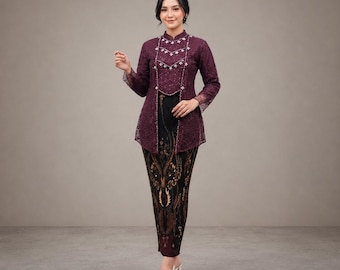 May include: A deep purple lace long-sleeve top with a high collar and white floral embroidery, paired with a floor-length black skirt featuring a brown and gold batik-style pattern. The outfit is completed with white slip-on shoes.