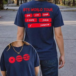 May include: Navy blue t-shirt with red text that reads "BTS WORLD TOUR" and the names of the band members. The lower portion of the shirt features a red graphic with the letters "OEE".