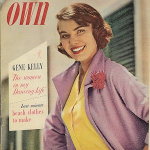 Peut inclure: Une couverture de magazine mettant en scène une femme vêtue d'une veste violette et d'un chemisier jaune. Le magazine s'intitule "Woman's Own" et présente le texte "Gene Kelly" et "The women in my Dancing Life".