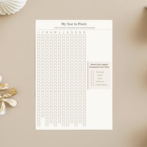 May include: A beige printable planner titled "My Year in Pixels" with a grid for daily mood tracking. The planner includes a mood color legend with options like "Amazing" and "Challenging".