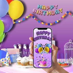 Może przedstawiać: Smartfon wyświetla grafikę "Happy Birthday", trzymany na fioletowym tle z balonami, babeczkami i dekoracyjnym banerem. Ekran telefonu pokazuje ciasto i balony. Kolorowe balony w tle.