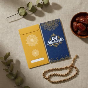 Puede incluir: Dos sobres decorativos, uno amarillo mostaza y otro azul marino, con diseños de mandala dorados. El sobre azul tiene el texto "Eid Mubarak" en blanco y dorado. Un cuenco de madera con dátiles y un rosario dorado también están presentes.