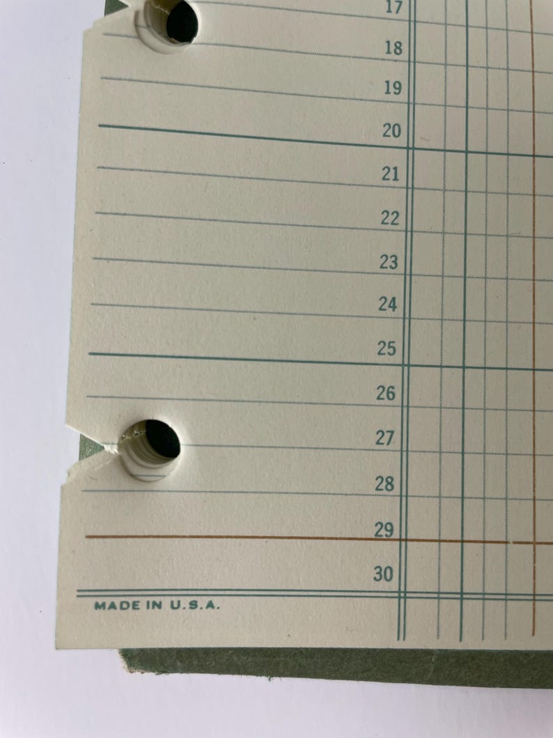 May include: Close-up of a vintage ledger paper with horizontal lines and vertical columns. The paper has two punched holes and the numbers 17 through 30 are visible. The text "MADE IN U.S.A." is printed at the bottom.