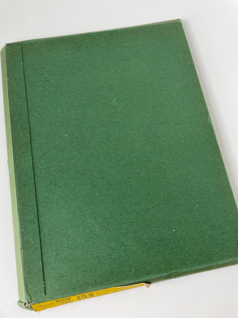 May include: A closed, green book with a textured cover. The spine is a darker shade of green. The bottom corner has a yellow label with black text. The book appears to be vintage or antique.