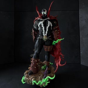 Peut inclure: Une figurine articulée Spawn vêtue d'un costume noir avec un emblème blanc sur la poitrine, une longue cape rouge et des chaînes argentées. Le personnage porte des gantelets et des bottes marron à pointes, une boucle de ceinture crâne.