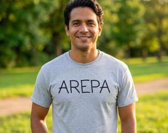 May include: A light gray short-sleeved t-shirt featuring the word AREPA printed in black capital letters across the chest. The garment has a classic crew neckline and a standard fit, constructed from a soft, heathered fabric material.