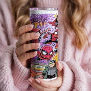 May include: A tall, cylindrical tumbler with a comic book design featuring Spider-Man illustrations. The tumbler has a purple background with a city skyline and text that reads "SP!" and "with great power... comes great responsibility."