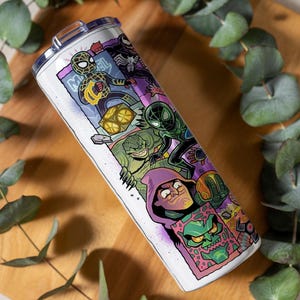 May include: A white stainless steel tumbler featuring a comic book-style illustration of Spider-Man and other Marvel characters. The design includes vibrant colours and the word "Marvel". The tumbler has a silver lid.