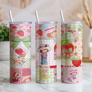 May include: Three cylindrical tumblers with white straws, each featuring a colorful collage of Strawberry Shortcake characters, red strawberries, pink gingham patterns, and green bows. The designs include illustrations of the character riding a horse.