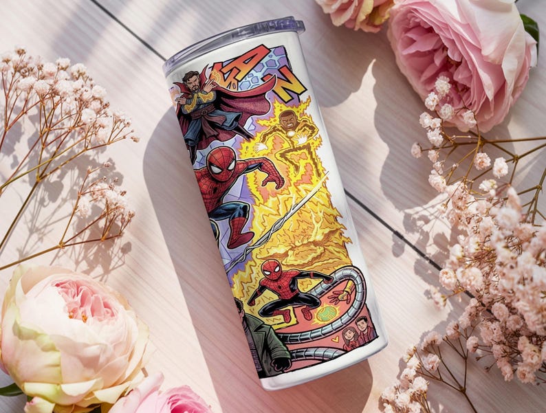 May include: A white cylindrical tumbler featuring a colorful comic book style graphic print of various superheroes including Spider-Man and Doctor Strange, with yellow lightning effects and a clear plastic lid on top of the beverage container.