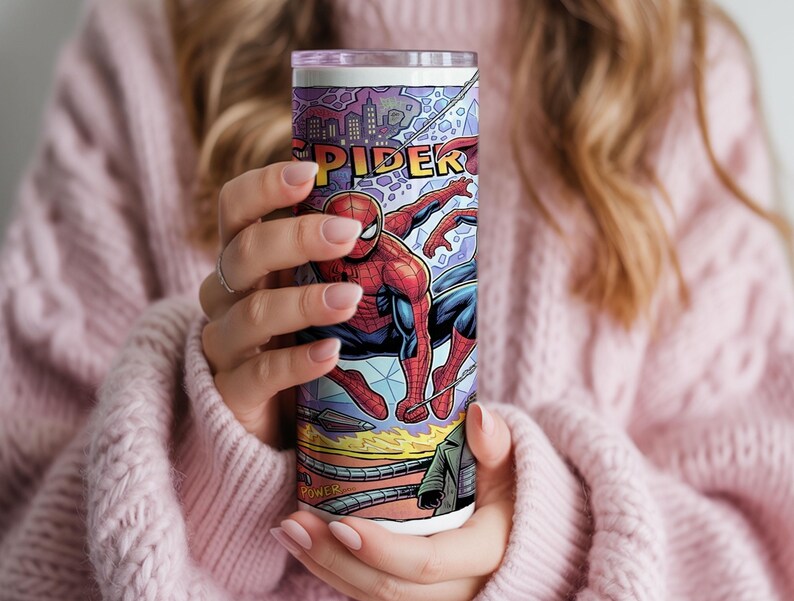 May include: A cylindrical tumbler featuring a vibrant comic book graphic of Spider-Man in a red and blue suit. The design includes a city skyline, the partial text SPIDER, and mechanical tentacles at the bottom against a purple and blue background.