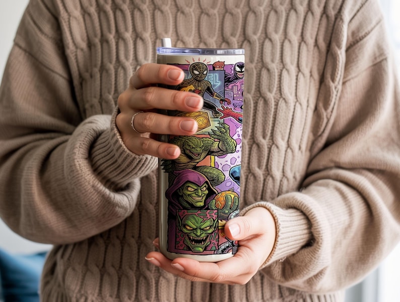 May include: A cylindrical stainless steel tumbler featuring a colorful comic book style graphic print of various characters including a spider-themed hero, a green reptilian creature, and a green-faced villain with a pointed purple hood.