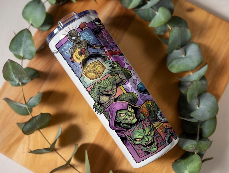 May include: A cylindrical white tumbler featuring a colorful graphic print of various comic book characters, including a masked hero in a black suit, a green reptilian creature, and a green-skinned villain wearing a purple hood and cape.